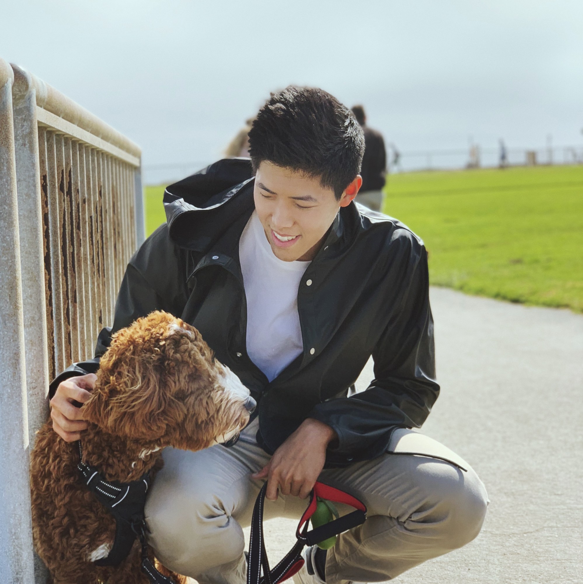 Justin crouching beside Peanut at a park.
